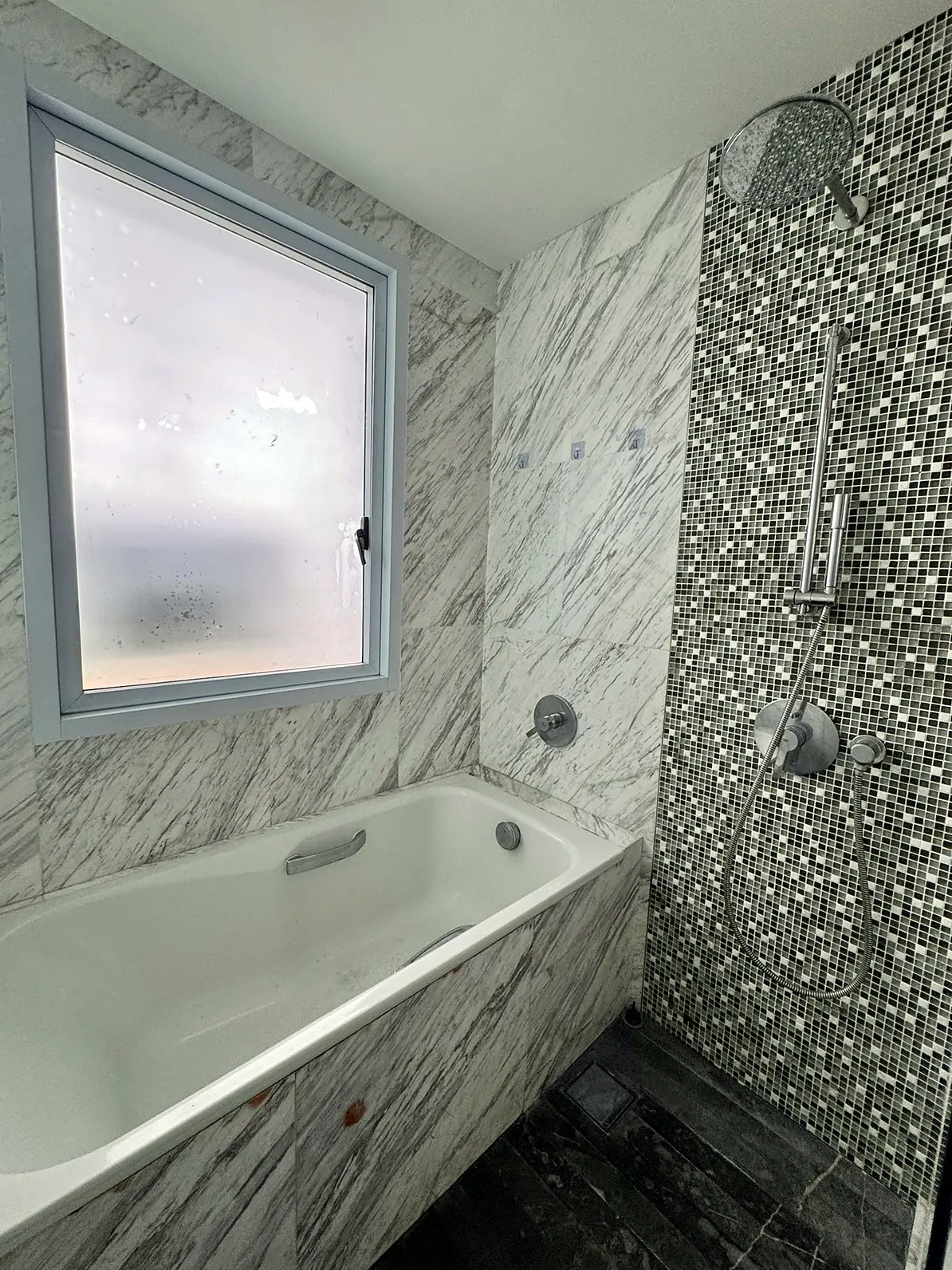 Private marble ensuite bathroom with bathtub and rain shower in Fifty Two Stevens Rumah Suite Room 1