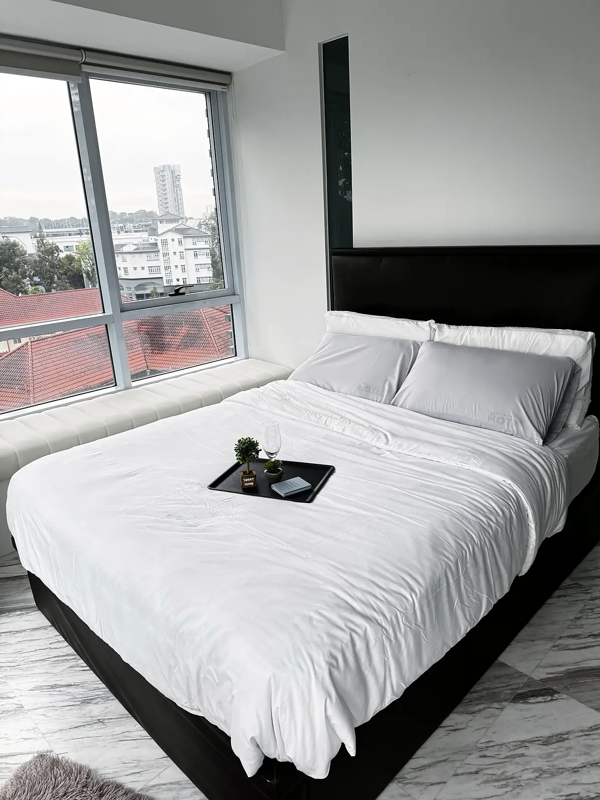 Queen bed with fresh white linen beside large windows in Fifty Two Stevens Rumah Suite Room 1