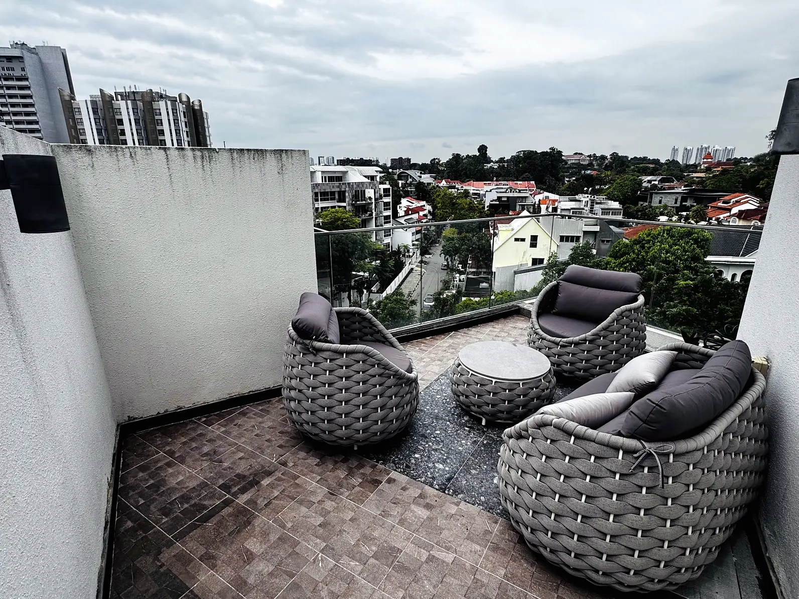 Outdoor deck with woven lounge chairs overlooking landed homes and greenery at Fifty Two Stevens